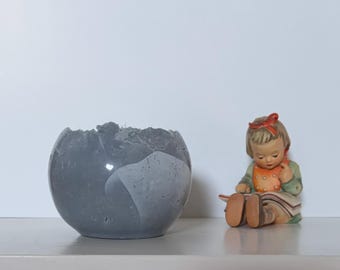 Small medium-gray concrete vessel sculpture. Sustainable. Live edge. Bowl with a natural shiny outside surface. Wabi-sabi style.