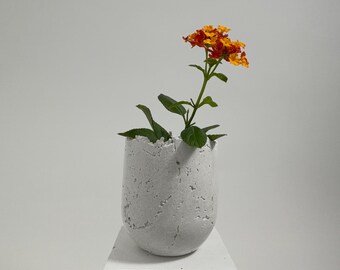 Small white concrete vessel sculpture. Sustainable. Live edge. Bowl with a natural shiny outside surface. Wabi-sabi style.