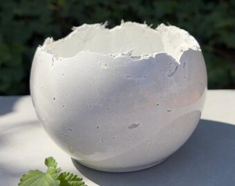 Small light-gray concrete vessel sculpture. Sustainable. Live edge. Bowl has a natural shiny outside surface. Wabi-sabi style.
