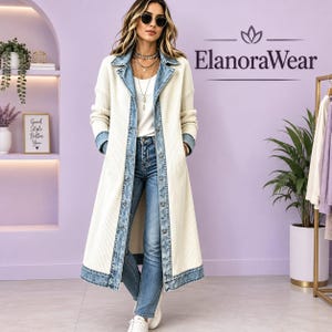 May include: A long, cream-colored ribbed knit duster coat featuring a blue denim collar, front placket, and hem trim. The coat is worn over a white top and blue jeans. The text ElanoraWear is visible in the upper right corner of the image.