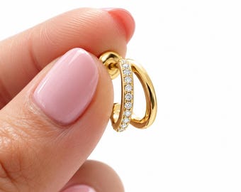 May include: A gold hoop earring featuring a double-band design. One band is smooth and polished, while the other is set with a row of small, clear, round-cut stones. The earring includes a standard post and a circular backing for secure closure.
