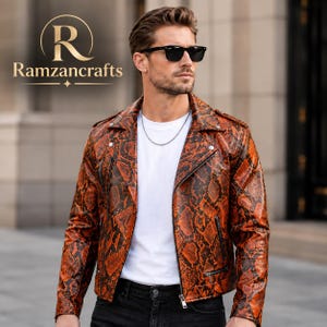 Puede incluir: Una chaqueta de motorista con un estampado de piel de serpiente en naranja y negro, solapas con muescas, cremalleras de metal plateado y botones a presión. La chaqueta se lleva sobre una camiseta blanca lisa con una cadena de plata y gafas.