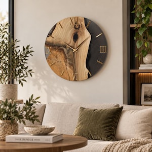 Puede incluir: Un reloj de pared circular con una esfera de madera natural y una incrustación de resina oscura. El reloj presenta números romanos dorados en las posiciones de las doce, tres, seis y nueve, junto con marcadores de hora dorados y manecillas finas.
