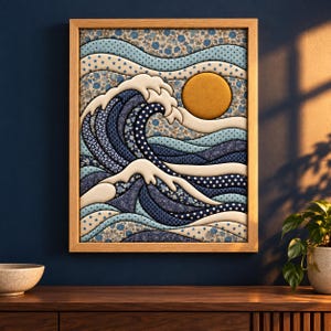 May include: A framed wall art piece featuring a layered fabric collage of a large ocean wave and a golden sun. The design uses various blue and white patterned textiles, including floral, polka dot, and paisley prints, with raised white foam edges.