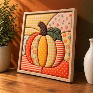 May include: A square framed wall art piece featuring a dimensional fabric pumpkin. The pumpkin is composed of various quilted fabric segments in orange, yellow, and white, displaying patterns of gingham, polka dots, stripes, and small floral prints.