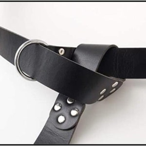 May include: A black leather belt with a silver buckle and metal accents. The belt is tied in a knot and has multiple rows of studs.