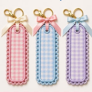 May include: Three rectangular embroidered keychains with scalloped edges and gingham patterns in pink, blue, and purple. Each features a gold-tone lobster clasp and a matching satin ribbon bow. Text reads Embroidery Club and PES, DST, JEF, VP3, EXP, HUS.