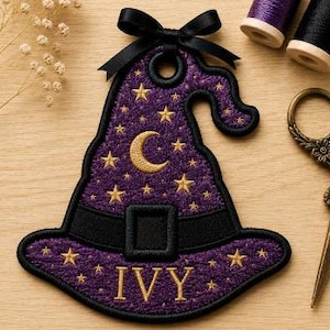 May include: A purple embroidered witch hat patch featuring gold stars and a crescent moon, a black band with a buckle, and the name IVY in gold thread. The patch is topped with a black ribbon bow and includes embroidery file formats listed below.