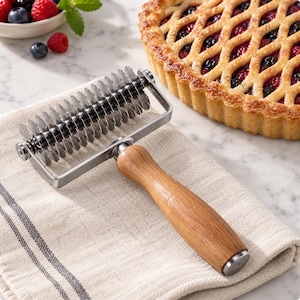 May include: A pastry lattice cutter featuring a series of circular, serrated stainless steel blades mounted on a metal frame with a smooth, light brown wooden handle. The tool is designed for creating decorative patterns in rolled dough.