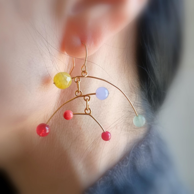 Peut inclure: Boucles d'oreilles en fil d'or avec des perles sph&eacute;riques color&eacute;es. Les boucles d'oreilles pr&eacute;sentent un design abstrait unique avec des perles rouges, jaunes, bleues et vertes. Les boucles d'oreilles sont con&ccedil;ues pour &ecirc;tre port&eacute;es &agrave; l'oreille.