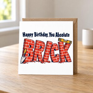 May include: A square greeting card with the text Happy Birthday, You Absolute BRICK in dark blue. The word BRICK is illustrated as red bricks with a small metal trowel on the left and a yellow spirit level resting on the letter K.