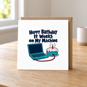 May include: A square greeting card with a white background featuring a dark blue laptop connected by a red cable to a blue frosted birthday cake with a single lit candle. The text reads: Happy Birthday It Works on My Machine.