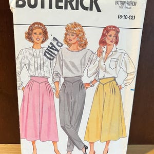 May include: Butterick sewing pattern 4264 for sizes 8-10-12. The envelope features illustrations of three outfits: a white patterned blouse with a pink skirt, a grey long-sleeve top with grey trousers, and a white collared shirt with a yellow skirt.