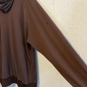 May include: A brown long-sleeved hooded sweatshirt. The sweatshirt has a dark brown hood and cuffs. The fabric appears to be soft and comfortable. The sleeve is angled towards the right side of the image.