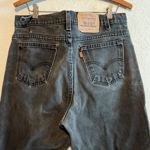K&ouml;nnte beinhalten: Schwarze Levi's 550 Jeans mit einem braunen Leder-Patch, auf dem "Levi Strauss & Co.  Original  Quality Clothing" und "550"  "W 34 L 34" steht.