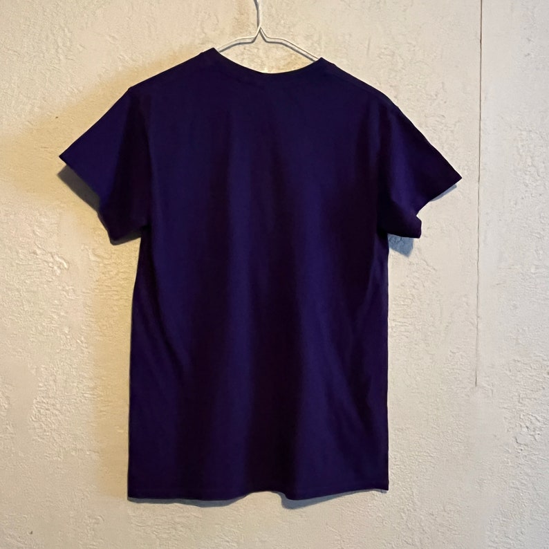 May include: A plain, dark purple t-shirt with short sleeves.