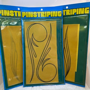 Könnte beinhalten: Drei Packungen mit Pinstriping-Aufklebern, die schwarze Schnörkel-Designs auf einem senfgelben Hintergrund zeigen. Jede Packung hat eine blaue Kopfzeile mit dem Wort PINSTRIPING in gelben Großbuchstaben, verpackt in einer Klarsichtfolie.