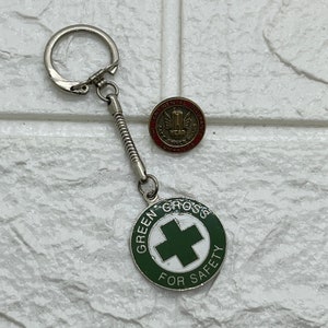 May include: A silver key chain with a green and white Green Cross for Safety charm and a small, round, gold Continental Insurance Companies pin.