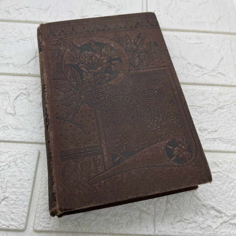 May include: A brown hardcover book titled Caxton Edition with an embossed floral design on the front cover. The cover features dark brown decorative patterns, including leaves and flowers, with the text Caxton Edition centered in a rectangular frame.