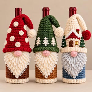 May include: Three crochet bottle covers shaped like gnomes. The first is red with white dots, the second is green with white trees, and the third features a small house design. Each has a long beard, a pink nose, and a pom-pom on the hat.