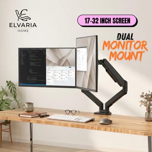 May include: A black dual monitor mount supporting two screens, one horizontal and one vertical. The mount is labelled 17-32 INCH SCREEN and DUAL MONITOR MOUNT. The setup includes a white keyboard, a grey mouse, a notebook, and a mug on a wooden desk.