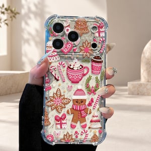 Può includere: Una cover trasparente per telefono con un motivo festivo natalizio raffigurante omini di pan di zenzero, bastoncini di zucchero, tazze di cioccolata calda, regali e alberi di Natale nei toni del rosa, bianco e marrone.
