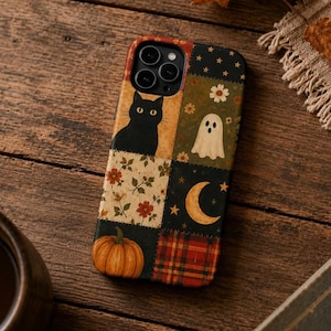 Puede incluir: Una funda de teléfono rectangular con un diseño de patchwork que incluye varias ilustraciones como un gato negro, un fantasma blanco, una luna creciente, una calabaza, motivos florales y una sección de cuadros rojos y negros.