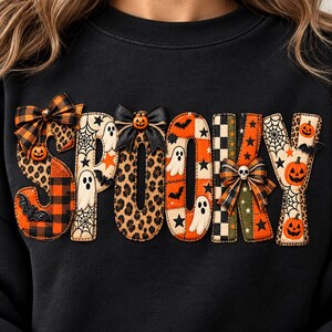 Könnte beinhalten: Ein schwarzes Sweatshirt mit dem Wort SPOOKY in großen, dekorativen Buchstaben. Jeder Buchstabe zeigt ein einzigartiges Muster, darunter orange-schwarzes Karomuster, Leopardenmuster, Geister, Spinnennetze, Fledermäuse, Sterne und Kürbisse.