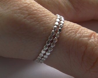 Puede incluir: Un anillo de plata con un diseño texturizado. El anillo está hecho de pequeñas cuentas redondas que están conectadas entre sí.