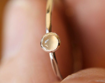 May include: A delicate silver ring with a small, round, white gemstone.