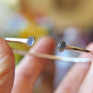 May include: A silver bangle bracelet with two oval-shaped labradorite gemstones.