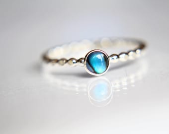 Könnte beinhalten: Ein silberner Ring mit einem blauen Abalone-Muschel-Edelstein. Der Ring hat ein Perlenband.