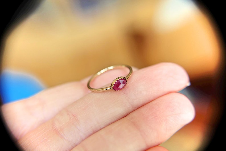 May include: A gold ring with a red ruby gemstone set in a bezel setting.