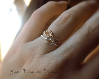 May include: Two gold rings intertwined in a knot design. The rings are worn on a finger and the caption "Best Friends Forever" is visible below.