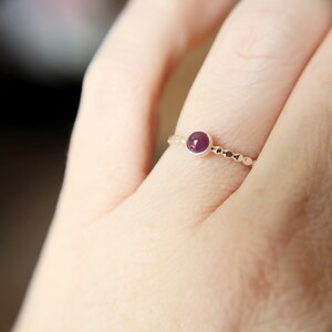 Puede incluir: Un anillo de plata con una peque&ntilde;a piedra preciosa redonda de color p&uacute;rpura engastada en el centro. El anillo est&aacute; hecho de peque&ntilde;as cuentas.