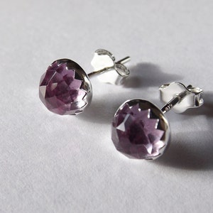 Peut inclure: Une paire de boucles d'oreilles en argent avec une pierre pr&eacute;cieuse violette au centre de chaque boucle d'oreille.