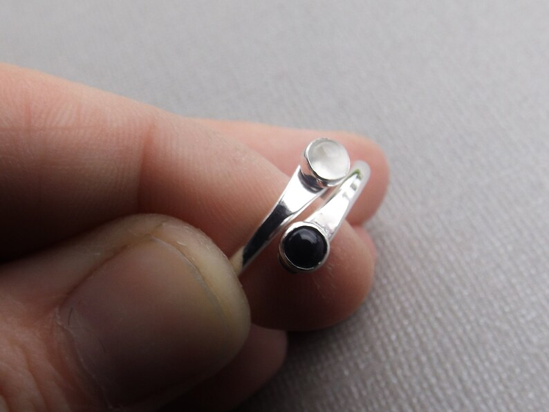 May include: A silver ring with two round stones, one white and one black.