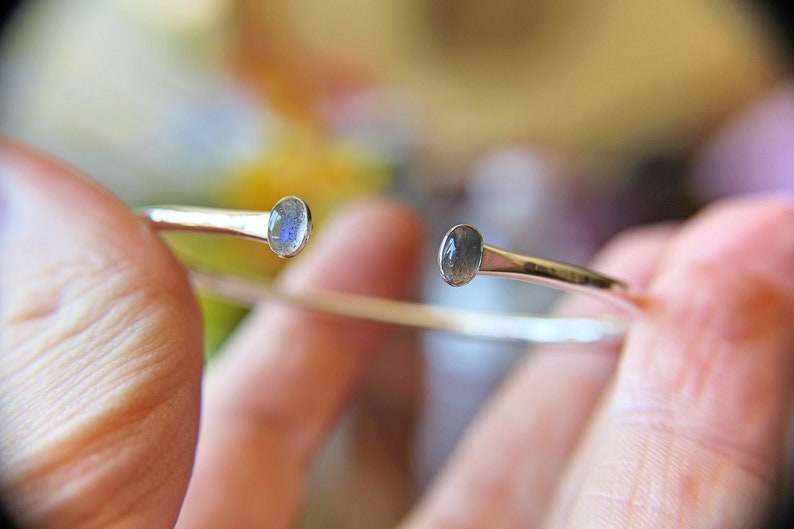 May include: A silver bangle bracelet with two oval-shaped labradorite gemstones.