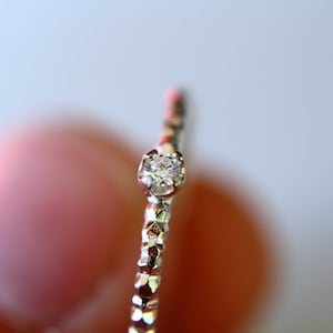 Puede incluir: Un anillo de plata con un solo diamante peque&ntilde;o y transparente engastado en el centro.
