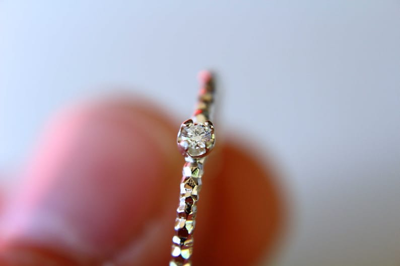 Puede incluir: Un anillo de plata con un solo diamante peque&ntilde;o y transparente engastado en el centro.