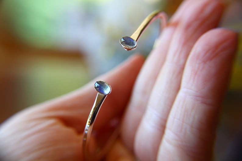 May include: A silver bangle bracelet with two oval-shaped blue gemstones set into the ends.