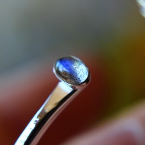 May include: A silver ring with a blue and gray oval gemstone.