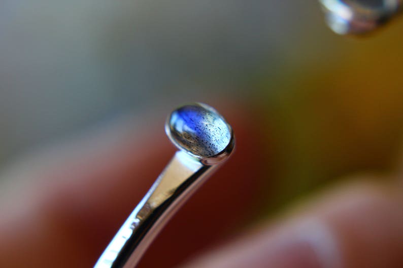 May include: A silver ring with a blue and gray oval gemstone.