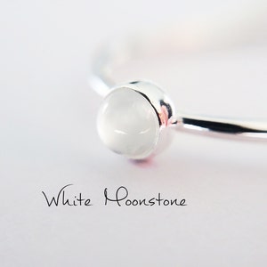 May include: A silver ring with a white moonstone. The ring is simple and elegant, and the moonstone is a beautiful, milky white.