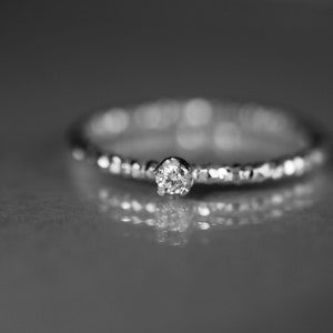 Puede incluir: Un anillo de plata con un solo diamante peque&ntilde;o y redondo engastado en el centro.