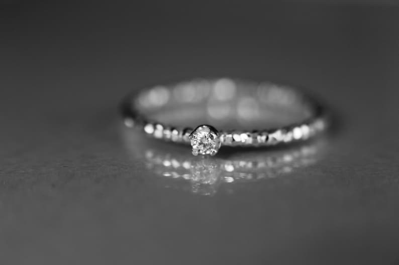 Puede incluir: Un anillo de plata con un solo diamante peque&ntilde;o y redondo engastado en el centro.