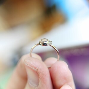 K&ouml;nnte beinhalten: Ein silberner Ring mit einem Marienk&auml;fer-Design. Der Marienk&auml;fer hat schwarze Punkte und einen silbernen K&ouml;rper.