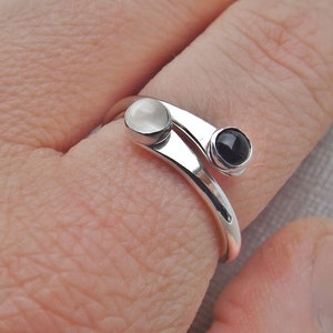 May include: A silver ring with a white and black stone. The ring is designed to wrap around the finger twice.