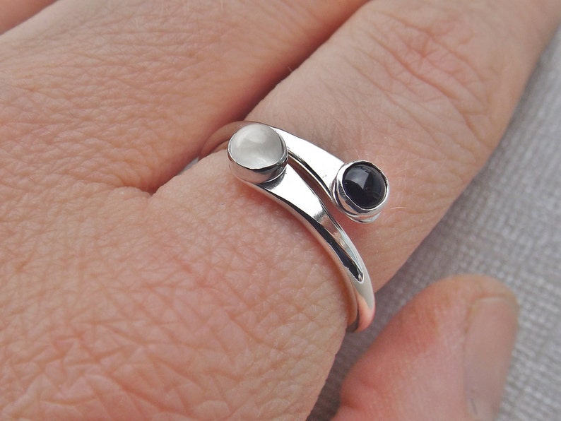 May include: A silver ring with a white and black stone. The ring is designed to wrap around the finger twice.