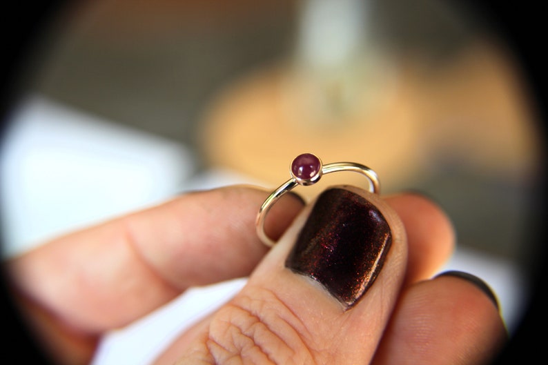 Peut inclure: Une simple bague en argent avec une seule pierre pr&eacute;cieuse ronde de couleur violet fonc&eacute;.